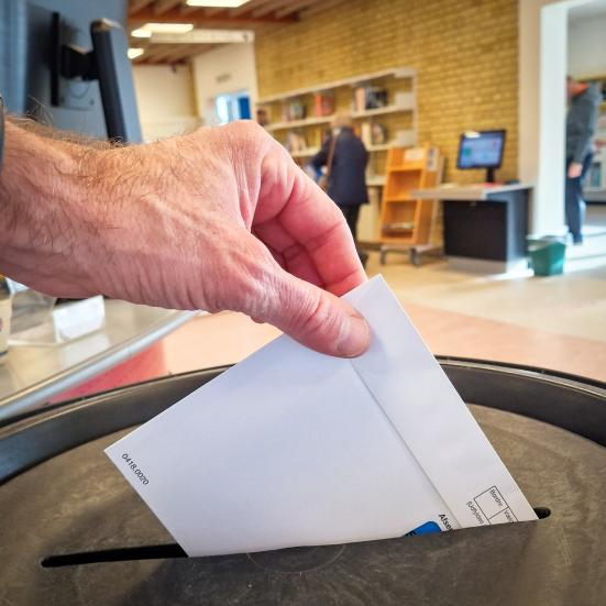 Fotografi af hånd der afleverer stemmeseddel