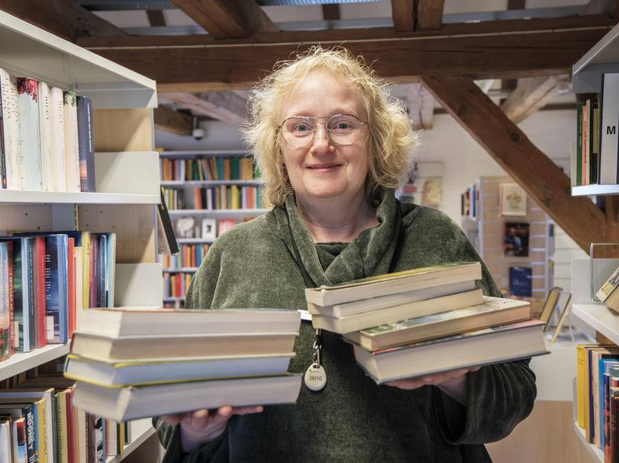 Foto af bibliotekar Dorte Hansen der står med to stakke bøger