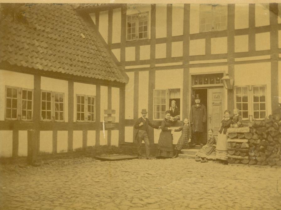 Billede fra apotekergården, Sorø Apotek. I døren står apoteker Glahn med familie ca. 1855. Hans datter Birgitte Glahn blev i 1909 den første kvindelige politiker i Sorø Byråd