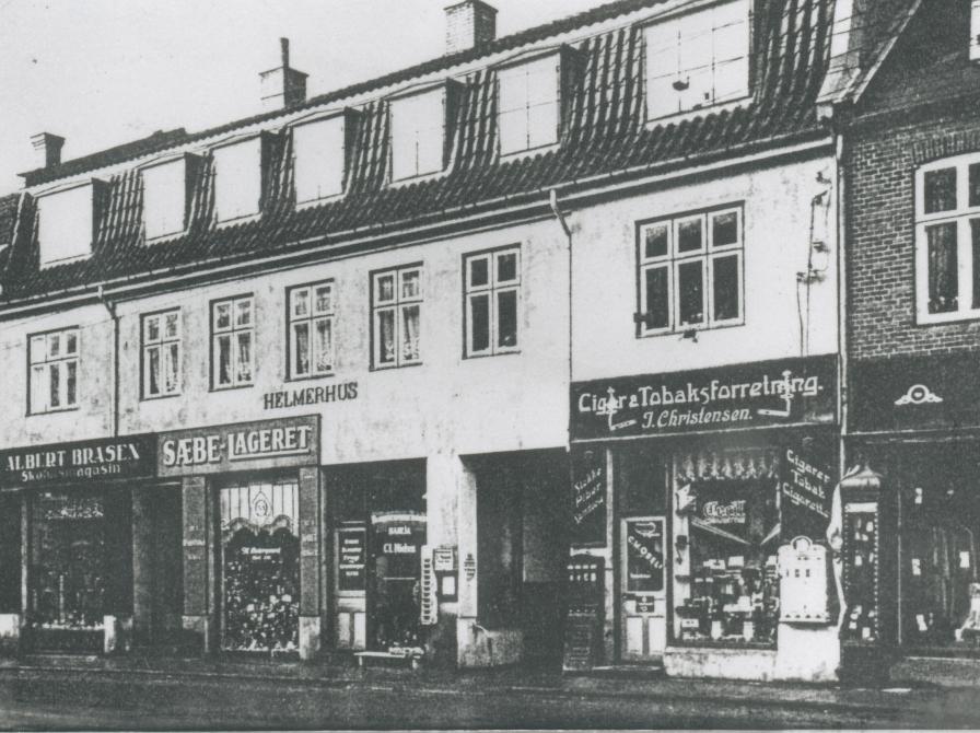 Helmerhus i starten af 1930'erne. Fra v. ses "Skotøjsmagasinet", hvis ejer var Albert Brasen, Sæbelageret, som blev bestyrer af Marie Østergaard og cigar- og tobaksforretning v/ I. Christensen
